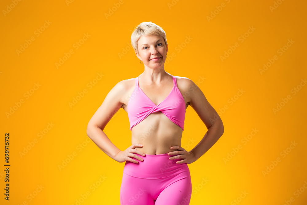 Fitness woman smiling and looking at camera on yellow background. Fitness woman smiling and looking at camera on yellow background.