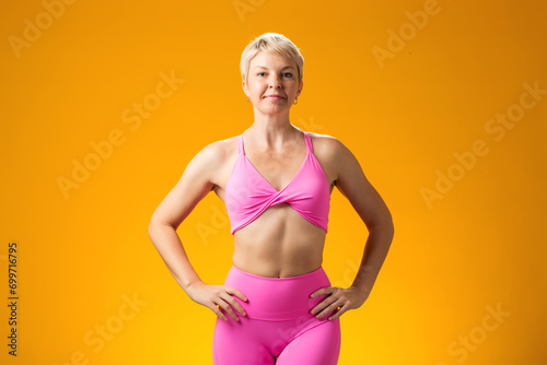 Fitness woman smiling and looking at camera on yellow background.