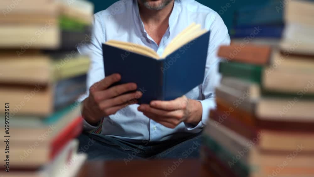 man reads a book - love of reading - man holds a book nestled among stacks of books in the library library man reads a book - love of reading - man holds a book nestled among stacks of books in the library library