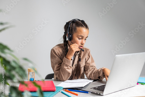 Online Education. Cute little Girl Study At Home With Laptop And Wireless Headphones, Adorable Kid Having Web Lesson With Teacher, Enjoying Distance Learning During Quarantine Time, Free Space photo