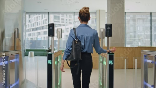 Businesswoman walking office exit passing turnstile with smartwatch back view photo