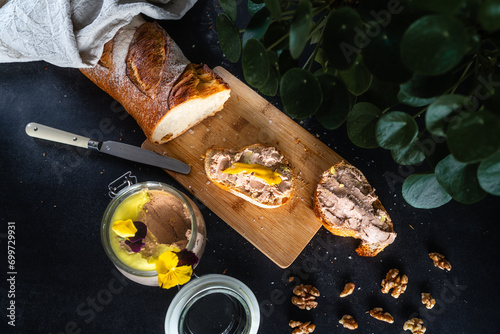 Vegane Foie Gras auf Holzbrettchen mit Senf auf Baguette auf schwarzem dunklen Untergrund photo