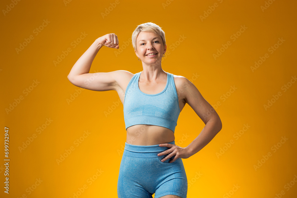 Fitness woman smiling and demonstrating biceps on yellow background. Fitness woman smiling and demonstrating biceps on yellow background.
