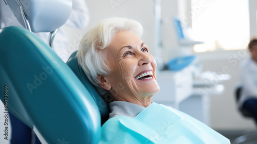 Elderly female patient with white hair, smiles happily while sitting in a dental chair
