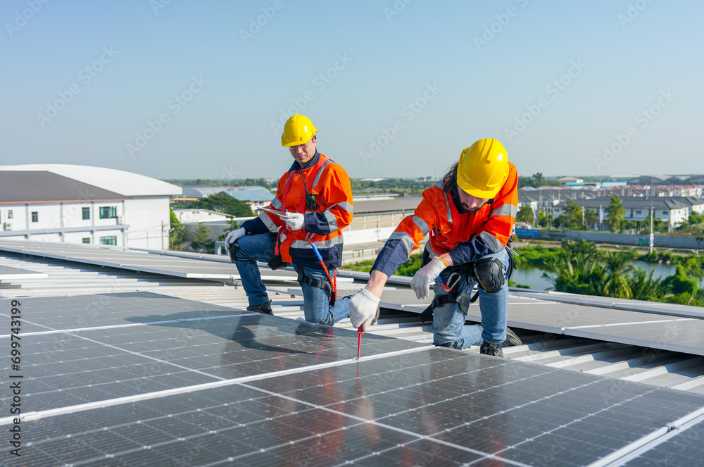 Caucasian technician workers use screwdriver to maintenance and fix the problem of the solar cell panels on rooftop of the building or factory. Caucasian technician workers use screwdriver to maintenance and fix the problem of the solar cell panels on rooftop of the building or factory.