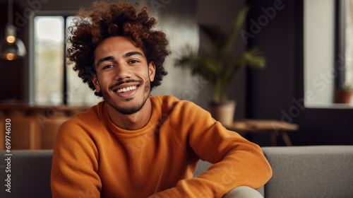 Portrait of a smiling man with curly hair wearing a rust-colored sweater, looking directly at the camera, with a warm and friendly expression photo