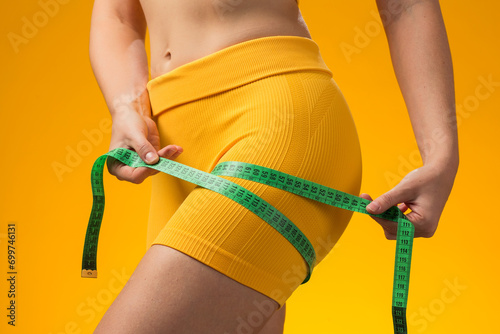 Fitness woman with measure tape isolated on yellow background. Weight loss and healthcare concept photo