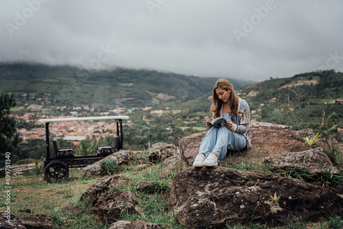 Teenager/woman reading a book on a hill