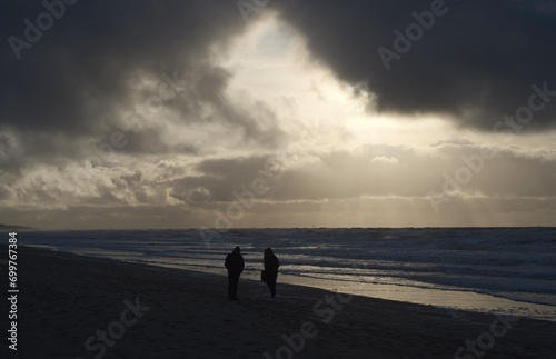 Paar vor wolkenreichem Himmel an der Nordseeküste