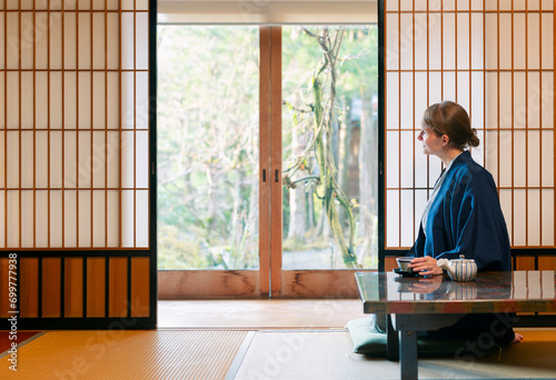 A young caucasian woman is relaxing at a traditional Japanese drinking a tea photo