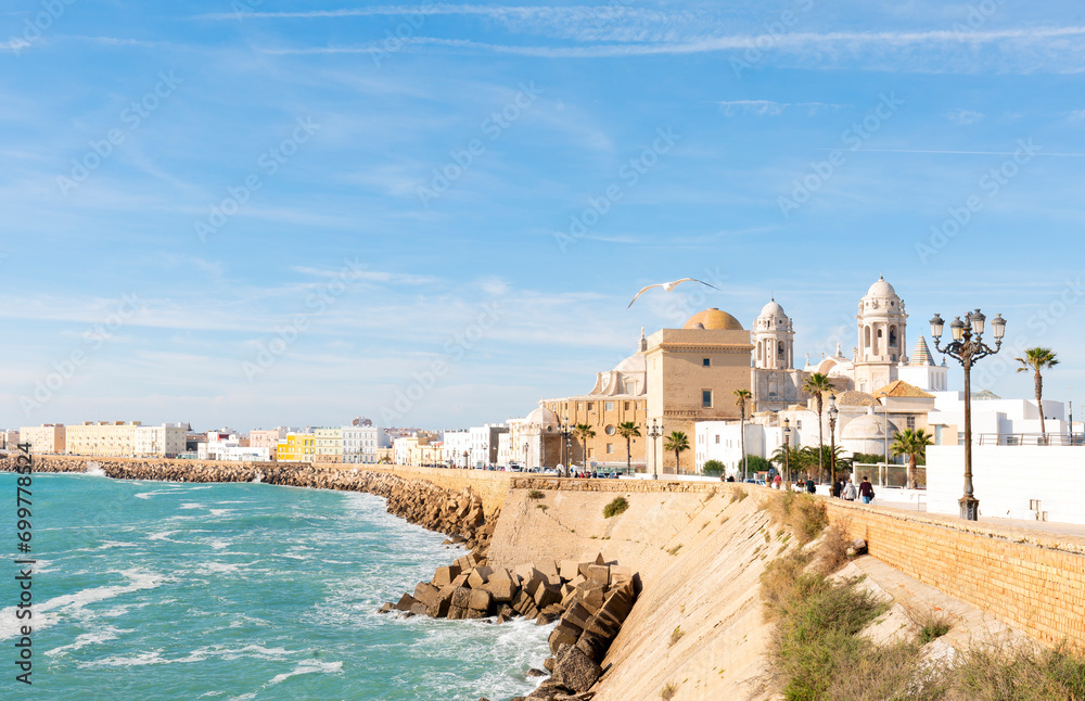 Beautiful view at day of the cathedral of Cadiz called cathedral de Santa Cruz with its 2 towers and its golden dome a blue sky and a blue ocean in Cadiz Andalusia Spain Europe.