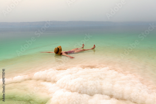Woman with hat relaxing in salty water of a Dead Sea photo