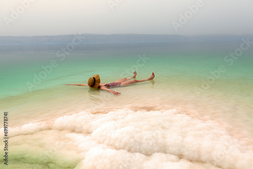 Woman with hat relaxing in salty water of a Dead Sea