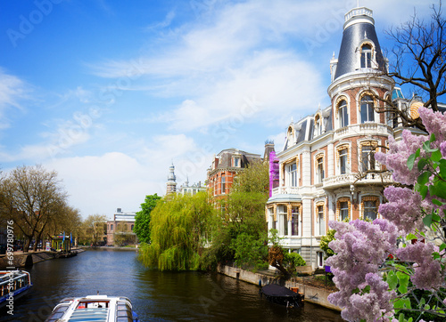 Photography One of canals in Amsterdam old town, Netherlands with lilac flowers, retro toned