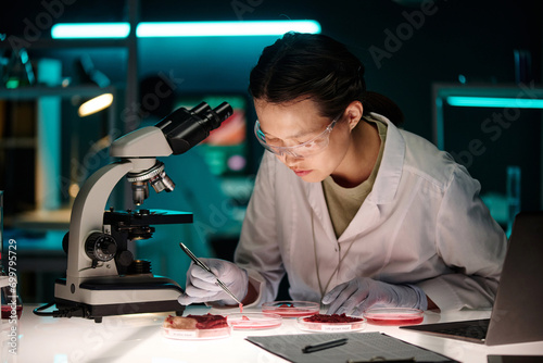 Billede på lærred Laboratory assistant comparing different kinds of meat in petri dishes sitting a