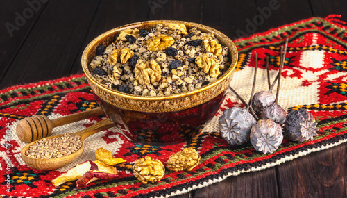 Ukrainian Christmas dish kutia, wheat porridge with nuts, poppy seeds, raisins in a vintage plate on the background of an embroidered towel. Ukrainian Christmas Eve