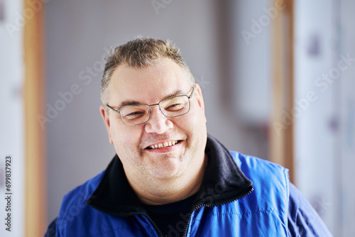 Large build man smiles cheekily, his face in glasses close-up