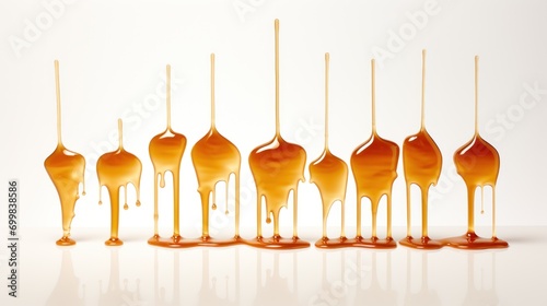  a group of spoons that are covered in caramel colored liquid and dripping on top of each other on a white surface.
