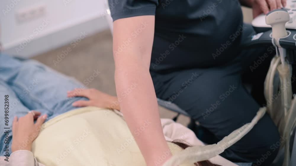 A doctor performs an ultrasound scan of the thyroid gland of a young woman in the clinic. The female is undergoing a medical examination. A doctor performs an ultrasound scan of the thyroid gland of a young woman in the clinic. The female is undergoing a medical examination.