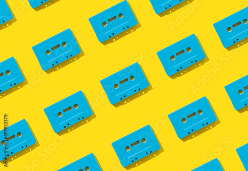 Pattern made with retro blue audio cassette tapes on yellow background. Creative concept of retro technology. 80's aesthetic. Vintage audio cassette tape pattern idea. Retro nostalgia. Flat lay.