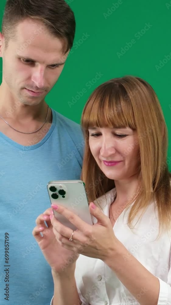 Picture of a young couple watching a funny video on mobile phone, posing on isolated background Picture of a young couple watching a funny video on mobile phone, posing on isolated background