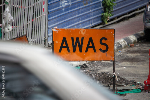 Фотография A cautionary 'AWAS' sign on a busy street construction site