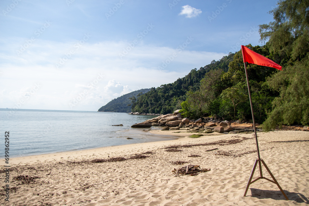 A serene beach scene with a red flag indicating caution.