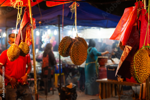 Принти на полотні Durian fruit hanging at a vibrant night market with bustling activity