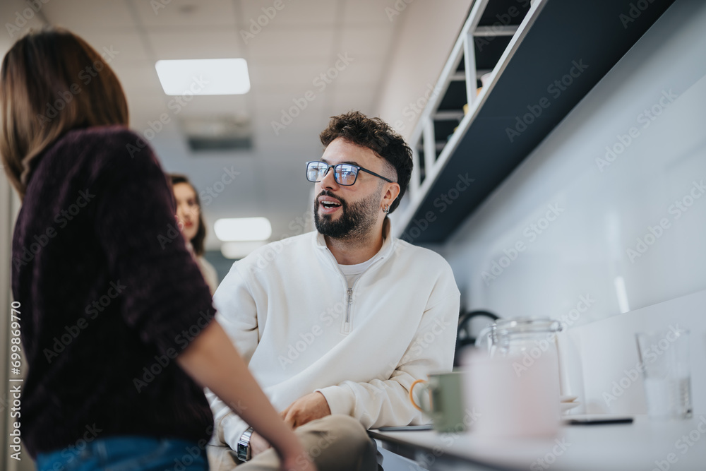 Fototapeta premium Positive atmosphere in a modern kitchen with coworkers having a conversation over morning coffee.