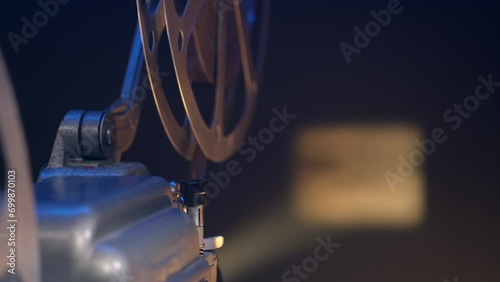 close up of antique movie projector projecting film on screen. 16mm projector brings back nostalgia of old films and cinemas. beam of light cuts through darkness, casting enchanting glow. photo