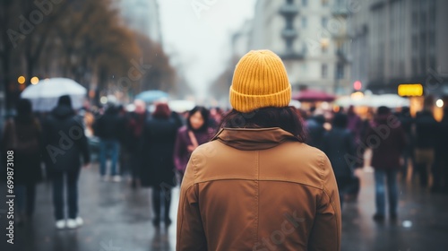 a person in a yellow jacket and a hat is walking down a street with a lot of people