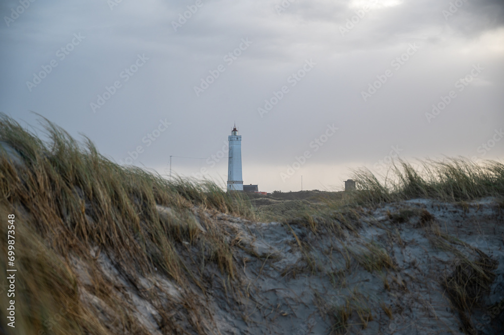 authentic beach scene from   western coast of denmark. The lighthouse of Blaavands huk in the background. - obrazy, fototapety, plakaty 