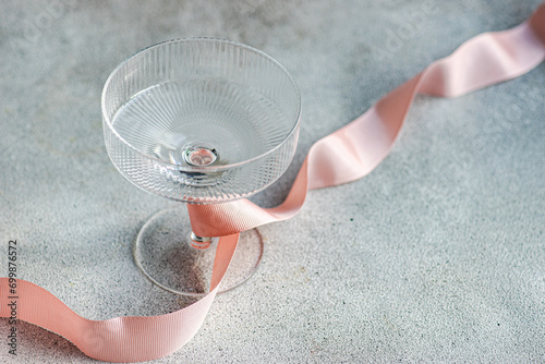 Close-up of a pink ribbon tied around an empty Champagne coupe photo