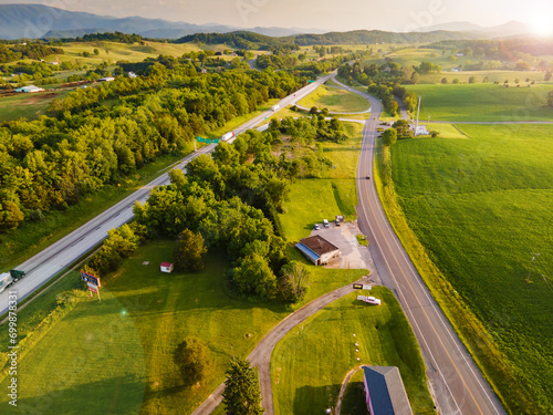 Aerial view of the road with cars.Beautiful landscape with a roadway, forest, houses, green meadows at sunset.
