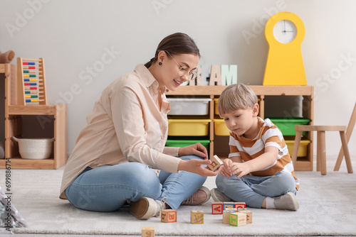 Nanny and little boy playing with cubes at home photo