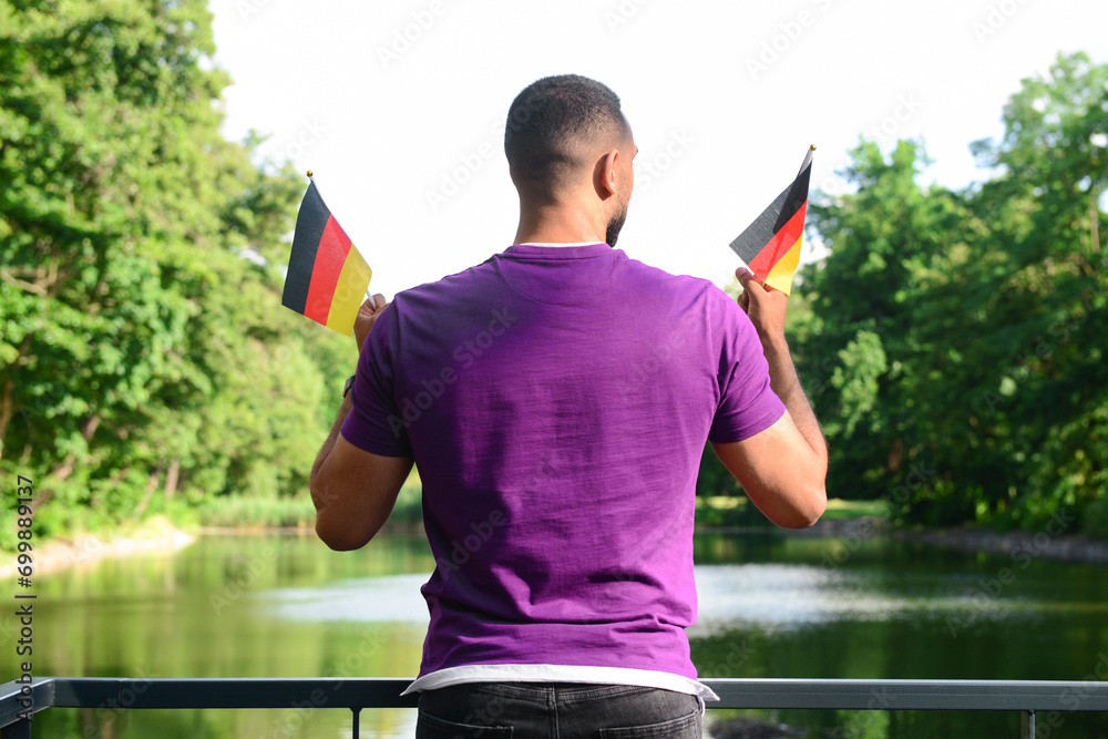 Young man with flags of Germany in park, back view