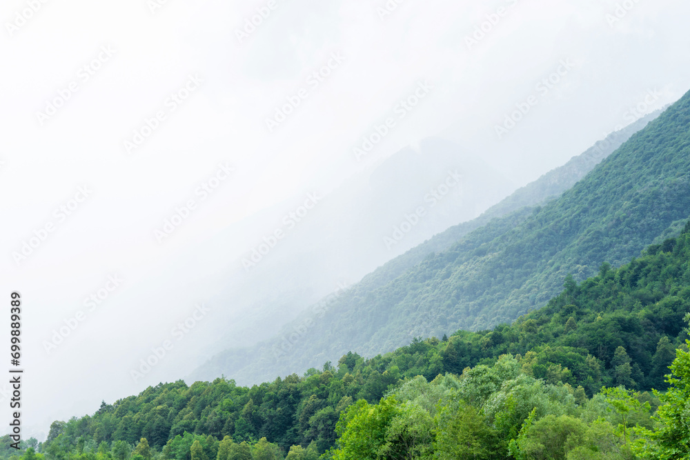 Obraz premium Beautiful landscape of the layered misty hazy Italian Alps mountain range during evening. Alpine summer sunrise. Lombardy, Italy