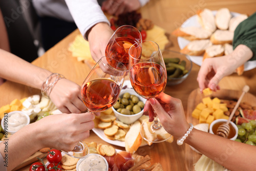 Konstfotografi People clinking glasses with rose wine at wooden table, above view