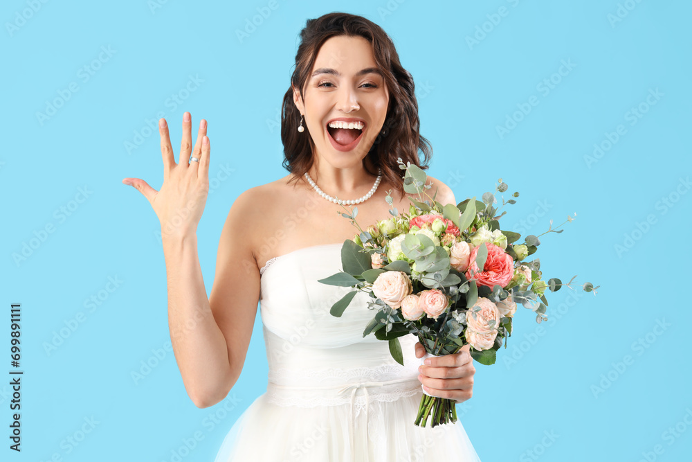 Beautiful bride with wedding ring and bouquet on blue background