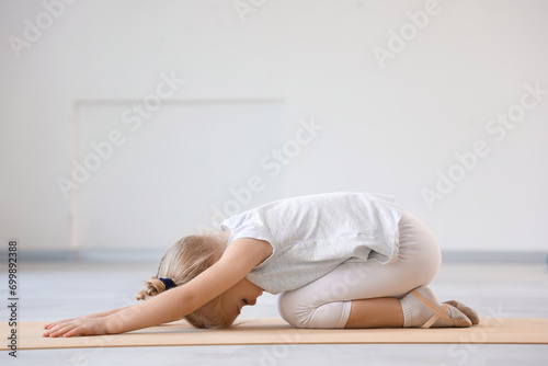 Cute little girl doing gymnastics on mat in gym