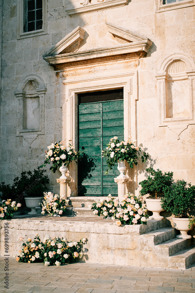 Wedding semi-arch with bouquets of flowers stands on the steps of St. Mark Church. Perast, Montenegro