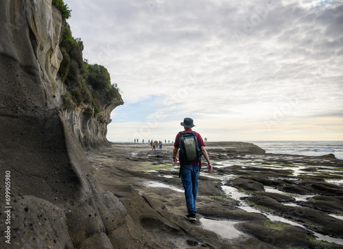 People walking and playing on rocks at Muriwai Beach in summer. Auckland. photo