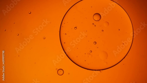 Gold artistic of oil drop floating on the water. Pastel color bubble for background. Orange background of oil drop.