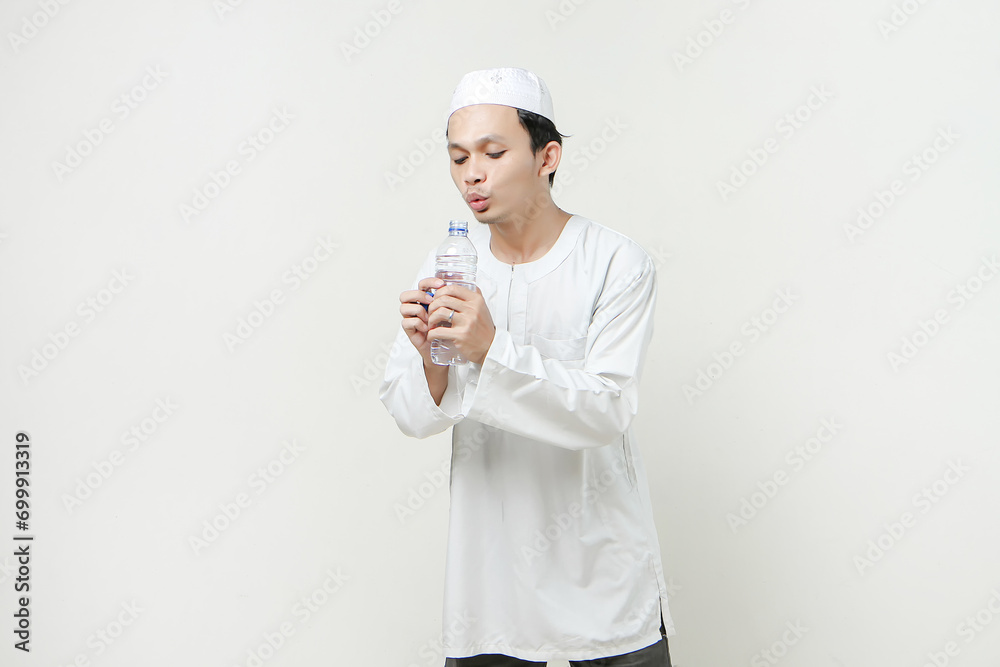 asian muslim man blowing ater bottle on isolated background asian muslim man blowing ater bottle on isolated background