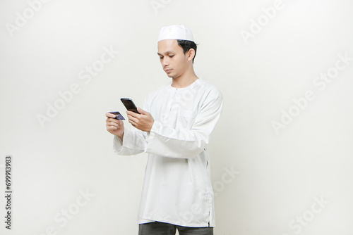 handsome asian man holding credit card and mobile phone on isolated background