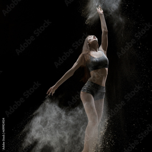 Girl in lingerie dancing in the dust in the dark