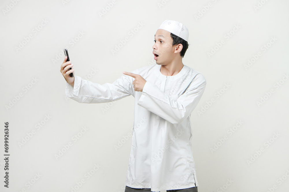  muslim man holding mobile phone and give shock expression. People religious Islam lifestyle concept. celebration Ramadan and ied Mubarak. on isolated background.