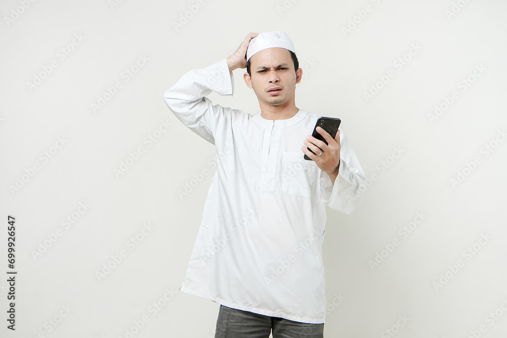 muslim man holding mobile phone and give stressful frustated expression. People religious Islam lifestyle concept. celebration Ramadan and ied Mubarak. on isolated backgroun. muslim man holding mobile phone and give stressful frustated expression. People religious Islam lifestyle concept. celebration Ramadan and ied Mubarak. on isolated backgroun.