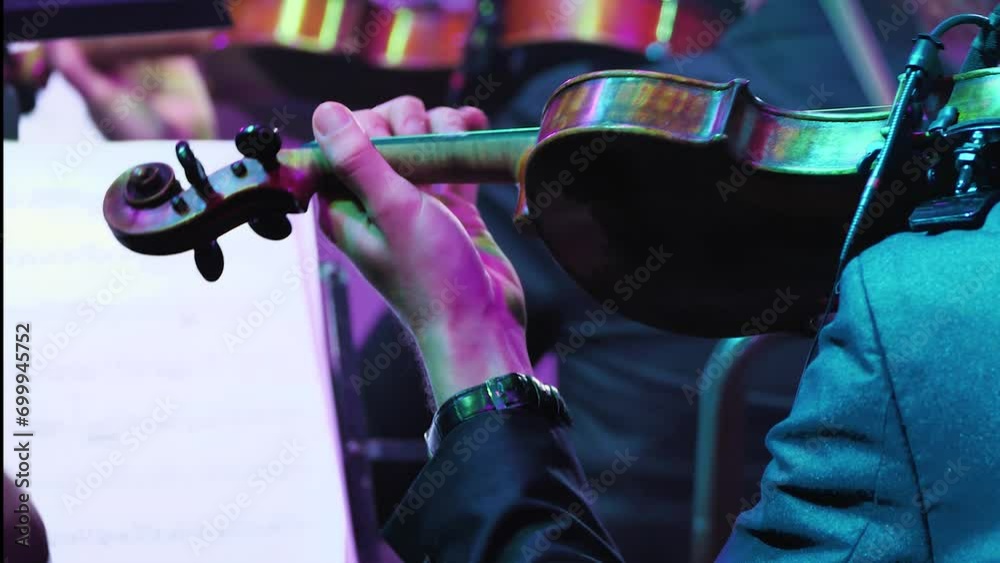 Detailed shooting, performance of a violinist on the stage. Violin in the hands of a professional musician of a symphony orchestra, playing on the stage of a classical theatre
