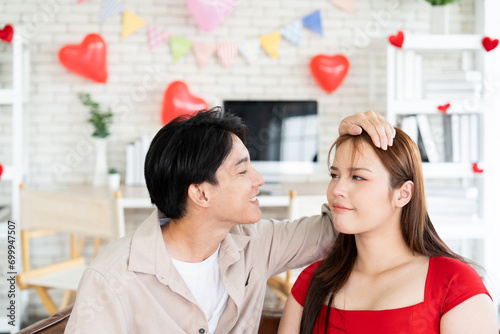 Asian pretty girlfriend angry and sulk when boyfriend forget about first dating anniversary while he reconcile and pretend pat on beloved head with heart balloons surprise in the living room apartment